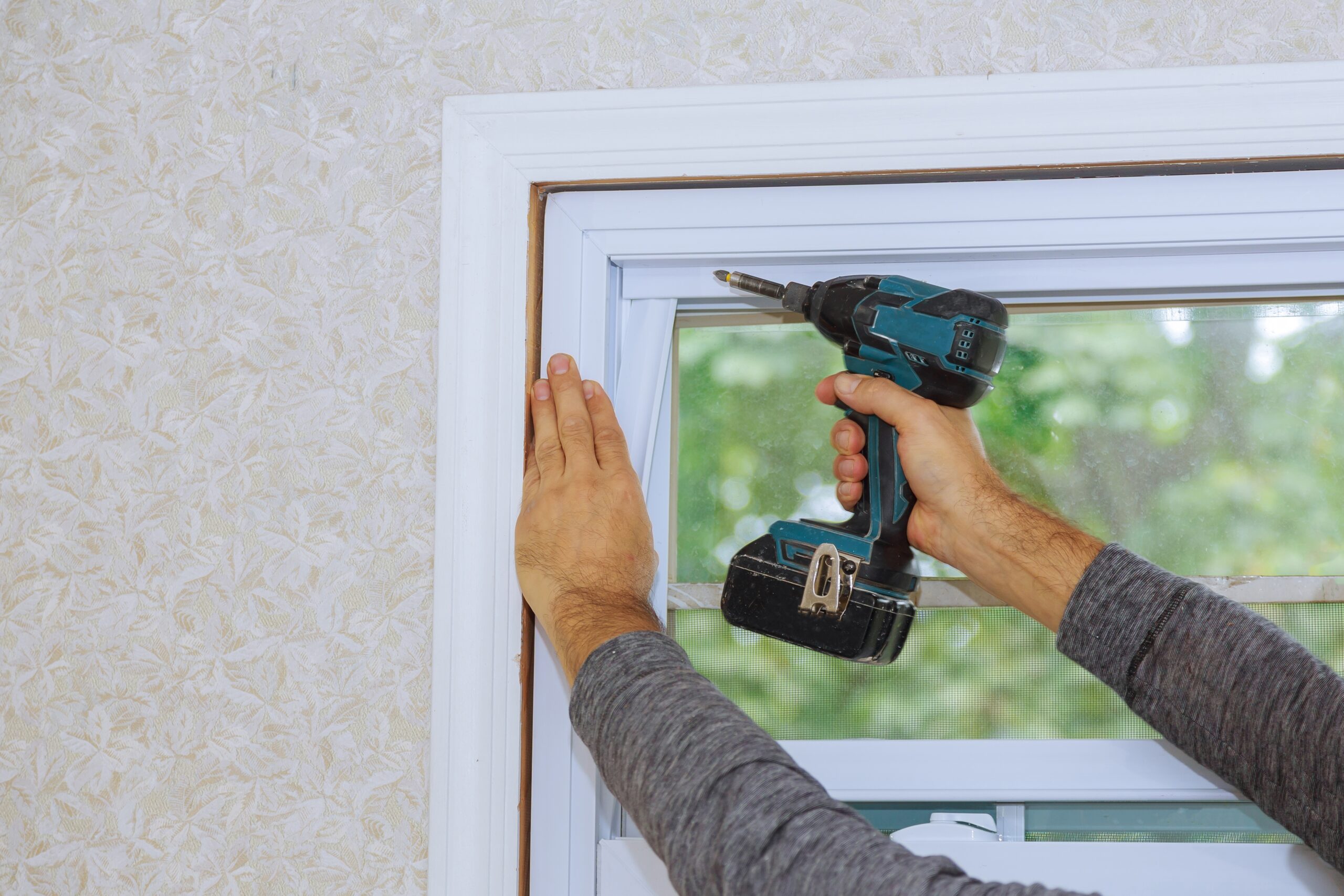 Process of worker installing new plastic pvc window man using a screwdriver